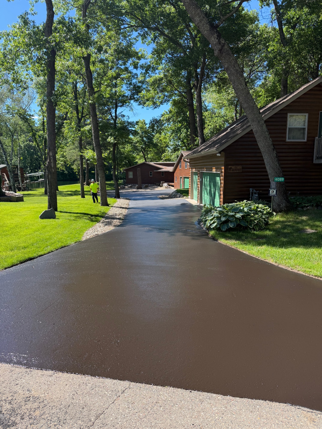 Same wooded residential driveway after seal coating with a deep black finish