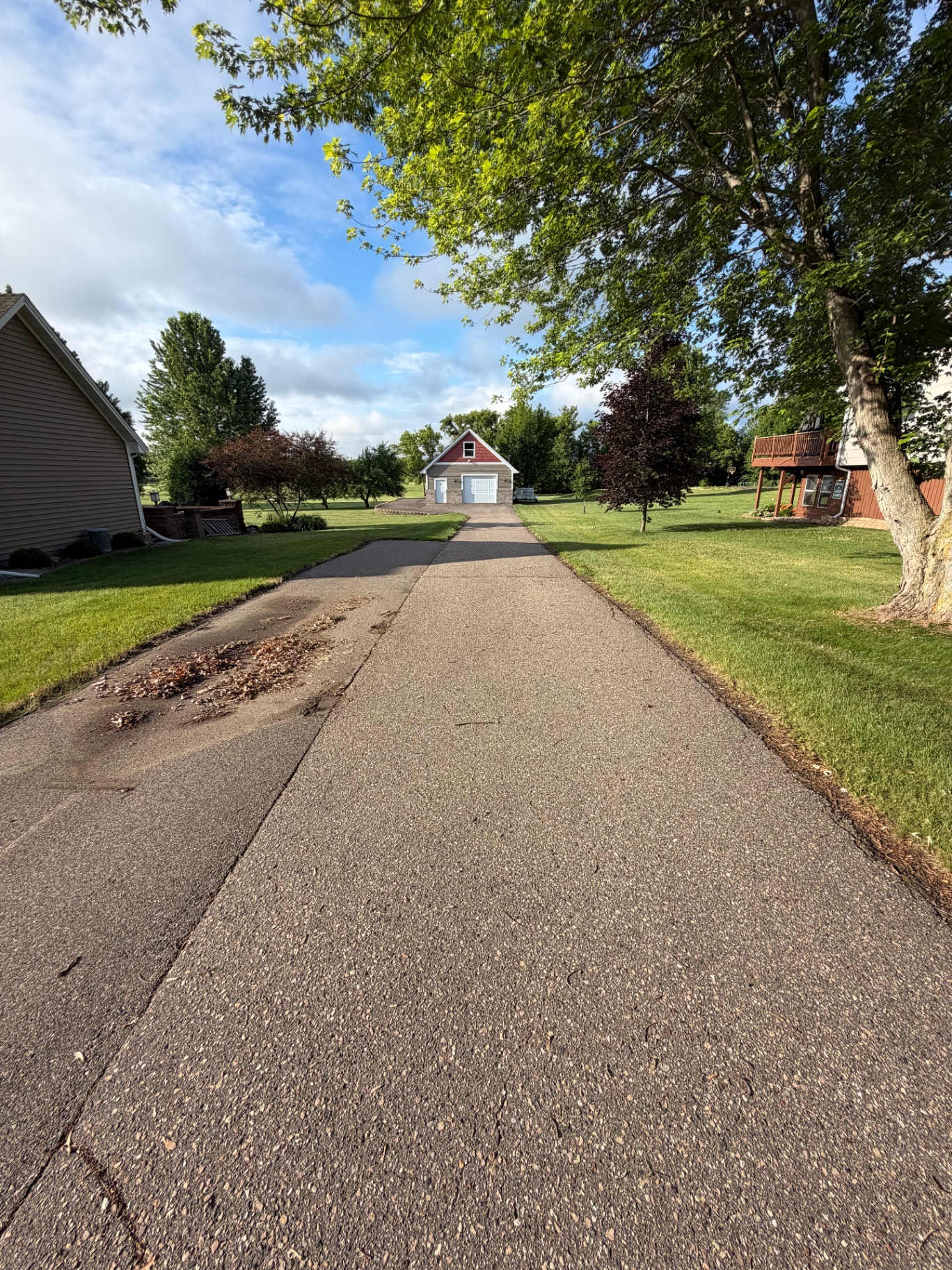 Residential asphalt driveway before seal coating leading to a detached garage