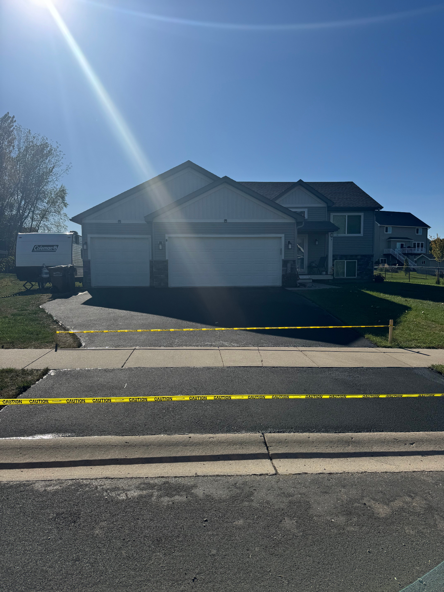 Same driveway after seal coating with a rich black finish and caution tape in place