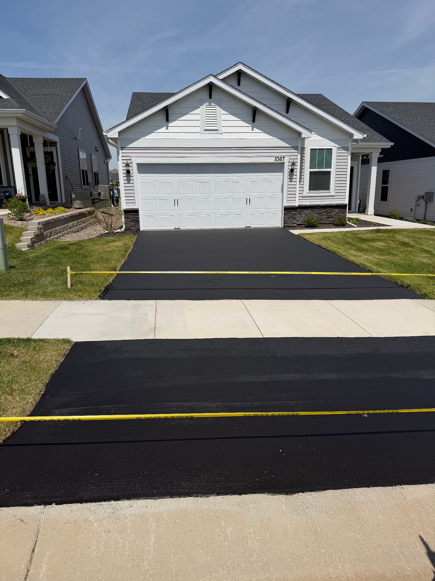 Same craftsman home driveway after seal coating with a deep, uniform black finish