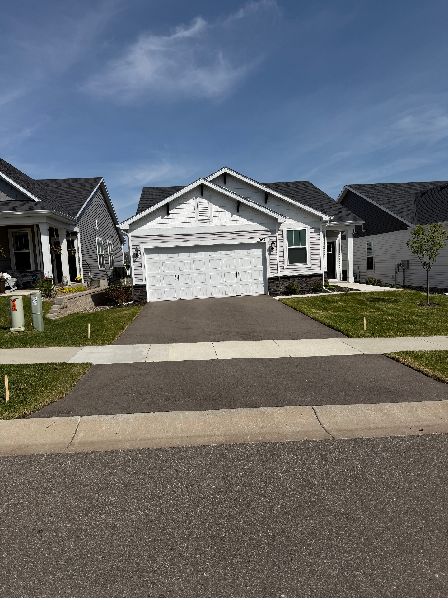 Faded asphalt driveway in front of a white craftsman home before seal coating