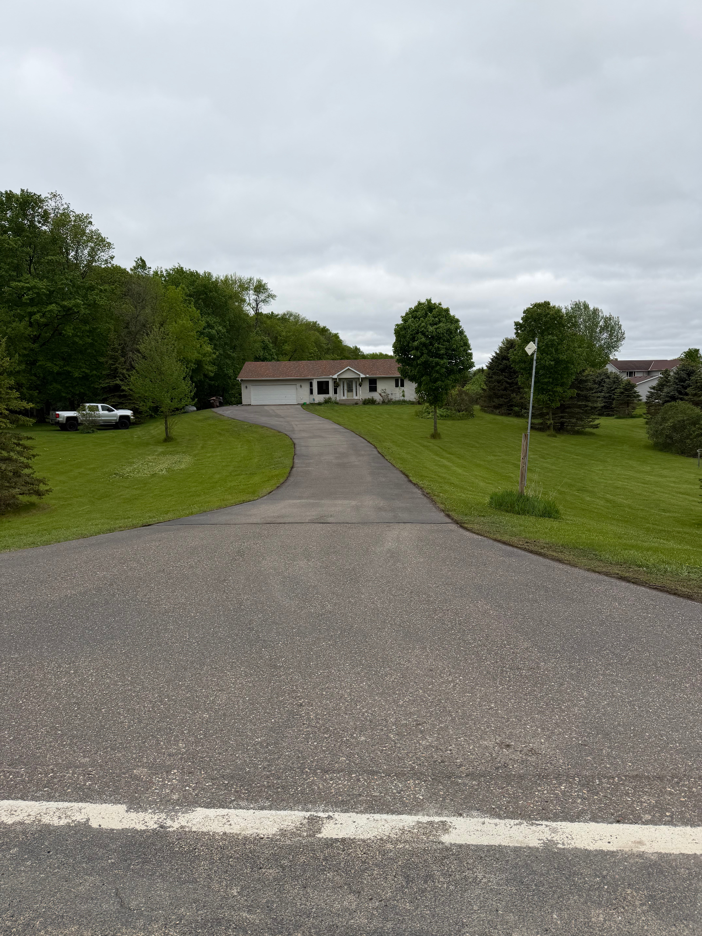 Long curved residential driveway before seal coating on an overcast day