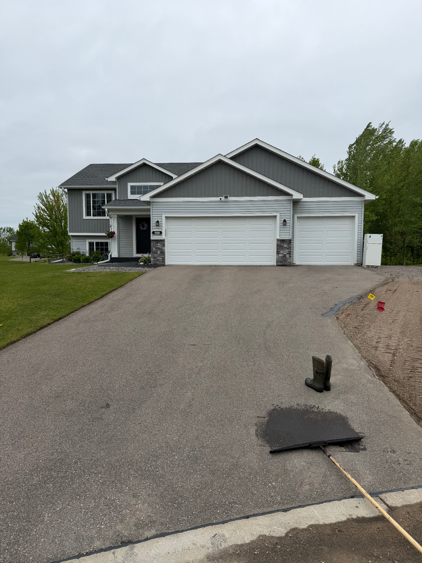 Residential driveway during preparation before seal coating with tools placed near the front edge