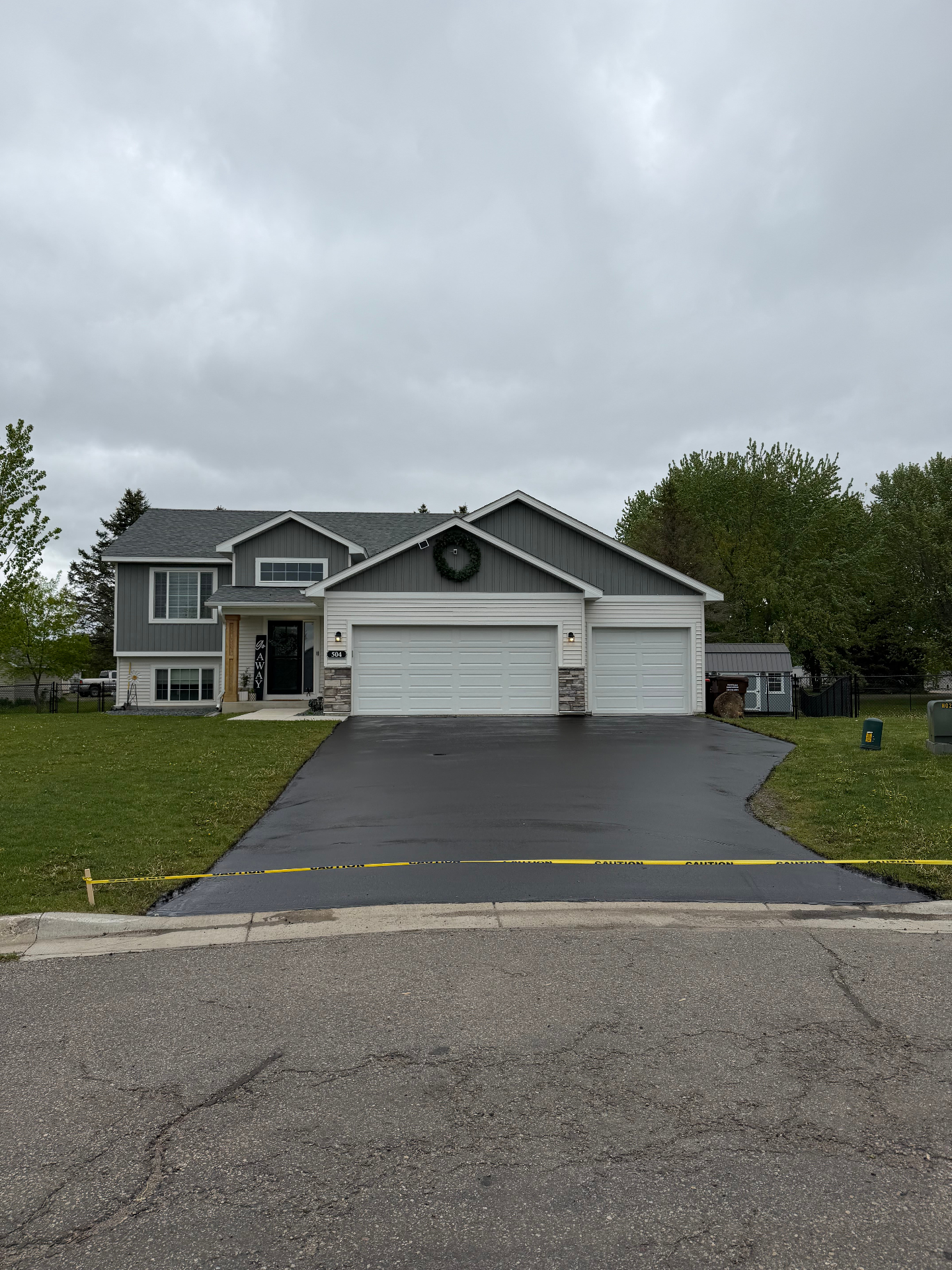 Freshly finished driveway in front of a gray home with stone accents